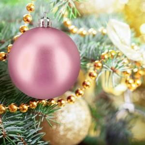 Glänzende rosa Weihnachtskugel aus Kunststoff am Tannenbaum. Christbaumschmuck mit silberner Aufhängung, umgeben von goldenen Perlen.