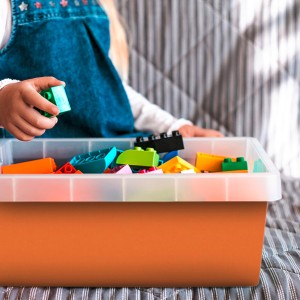 Orangefarbene Venilia Klebefolie (45x200cm) mit Kind und bunten Bauklötzen.