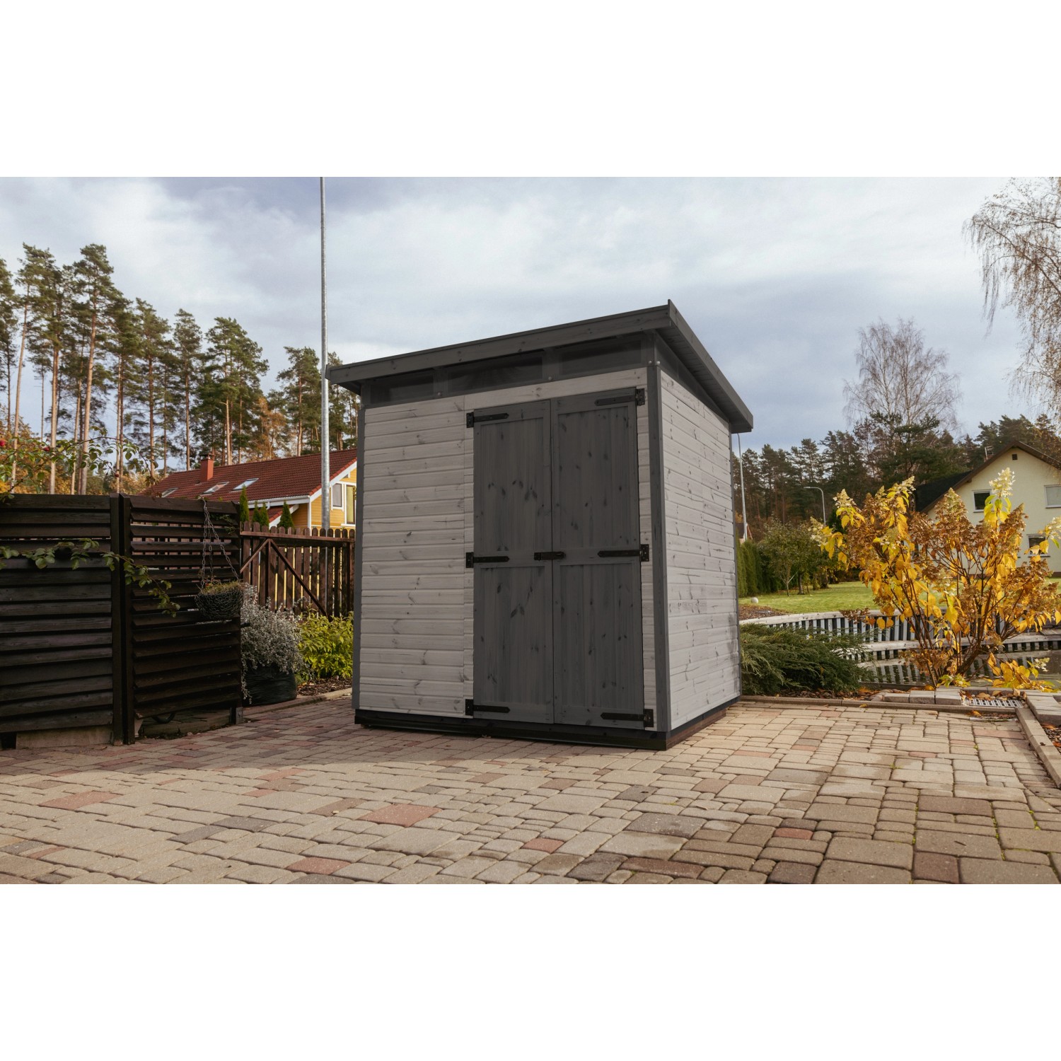 Graues Upyard Gartenhaus Strongbox L mit Doppeltür und Fundament im Garten.