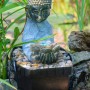 Zimmerbrunnen Buddha mit Lotusblüte in Steinoptik und Deko-Steinen.