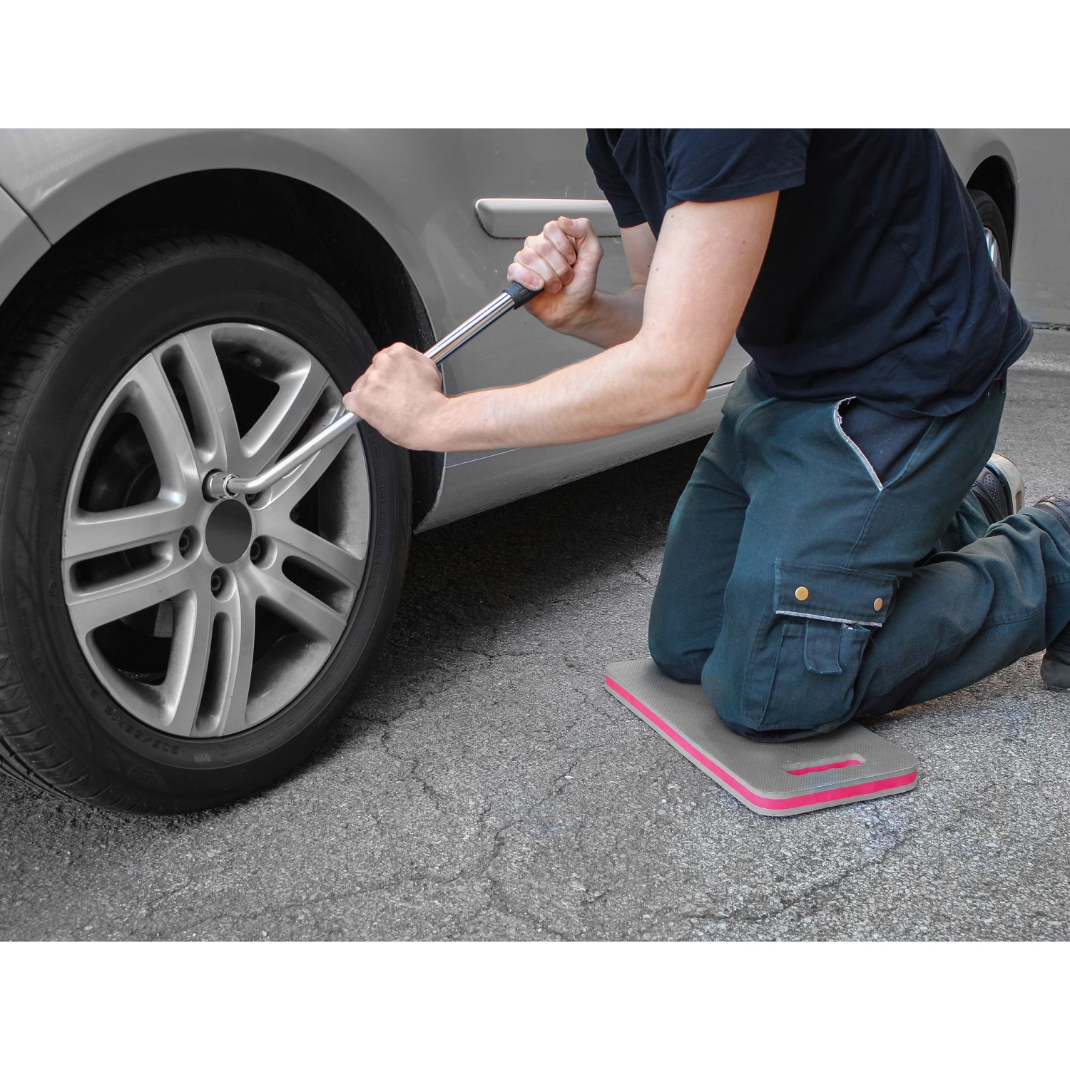 Mann wechselt Reifen mit Eufab Kniekissen für Komfort. Sonstige Wartung & Autoreparatur.
