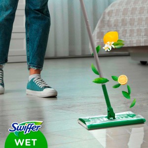 Swiffer Bodenwischer mit feuchtem Tuch im Einsatz, Zitrone und Blätter schweben in der Luft.