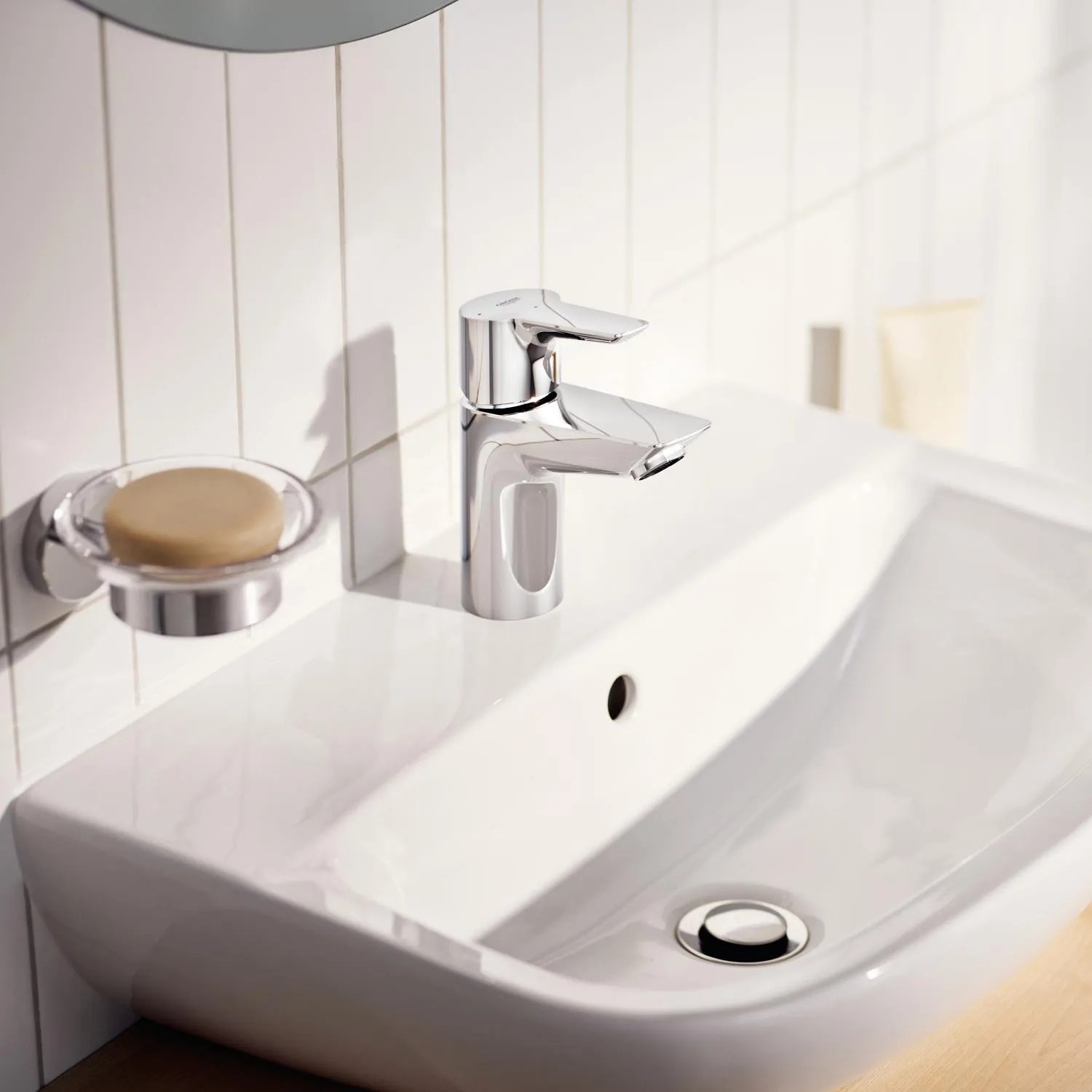 Glänzende Grohe QuickFix Waschtischarmatur Start Alira Chrom S auf einem weißen Waschbecken.