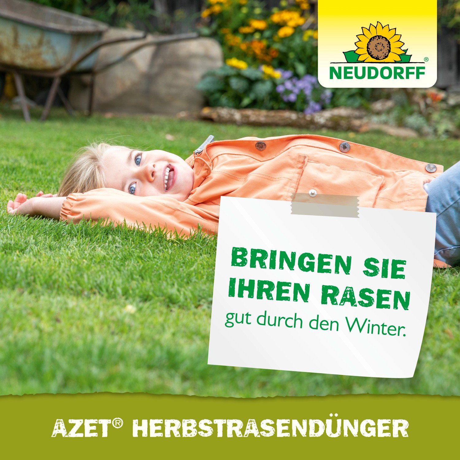 Kind liegt auf Rasen mit Neudorff Azet Herbst-Rasendünger Hinweis für Winterfestigkeit.
