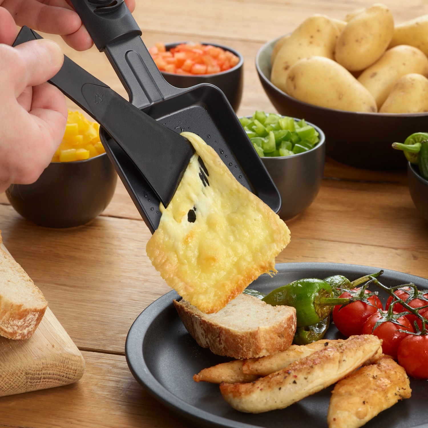 Severin Raclette-Grill RG 9670 mit Käse über Brot und Beilagen.