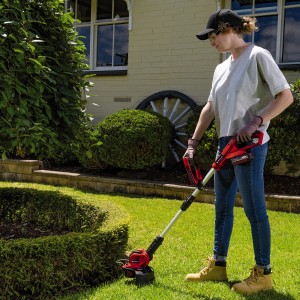 Frau trimmt Rasen mit Einhell Akku-Rasentrimmer GE-CT 18/28 Li mit Akku. Rasenkantenschneider im Einsatz.