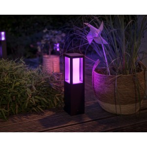 Philips Hue Impress Sockelleuchte, schwarzes Gehäuse mit violetter Beleuchtung im Garten.