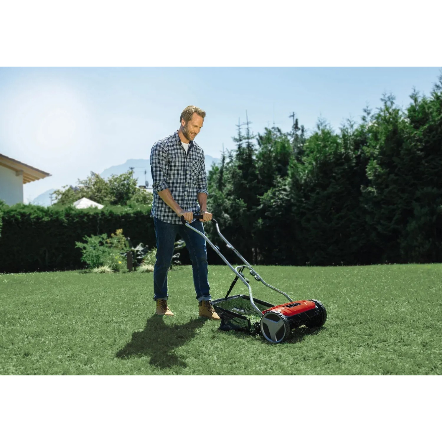 Einhell Hand-Rasenmäher GE-HM 38 S-F im Einsatz: Mann mäht Rasen mit dem roten Spindelmäher.