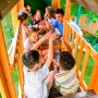 Kinder spielen auf dem Zwerkules Spielturm Bolzo mit Rutschen und Schaukel im Garten.