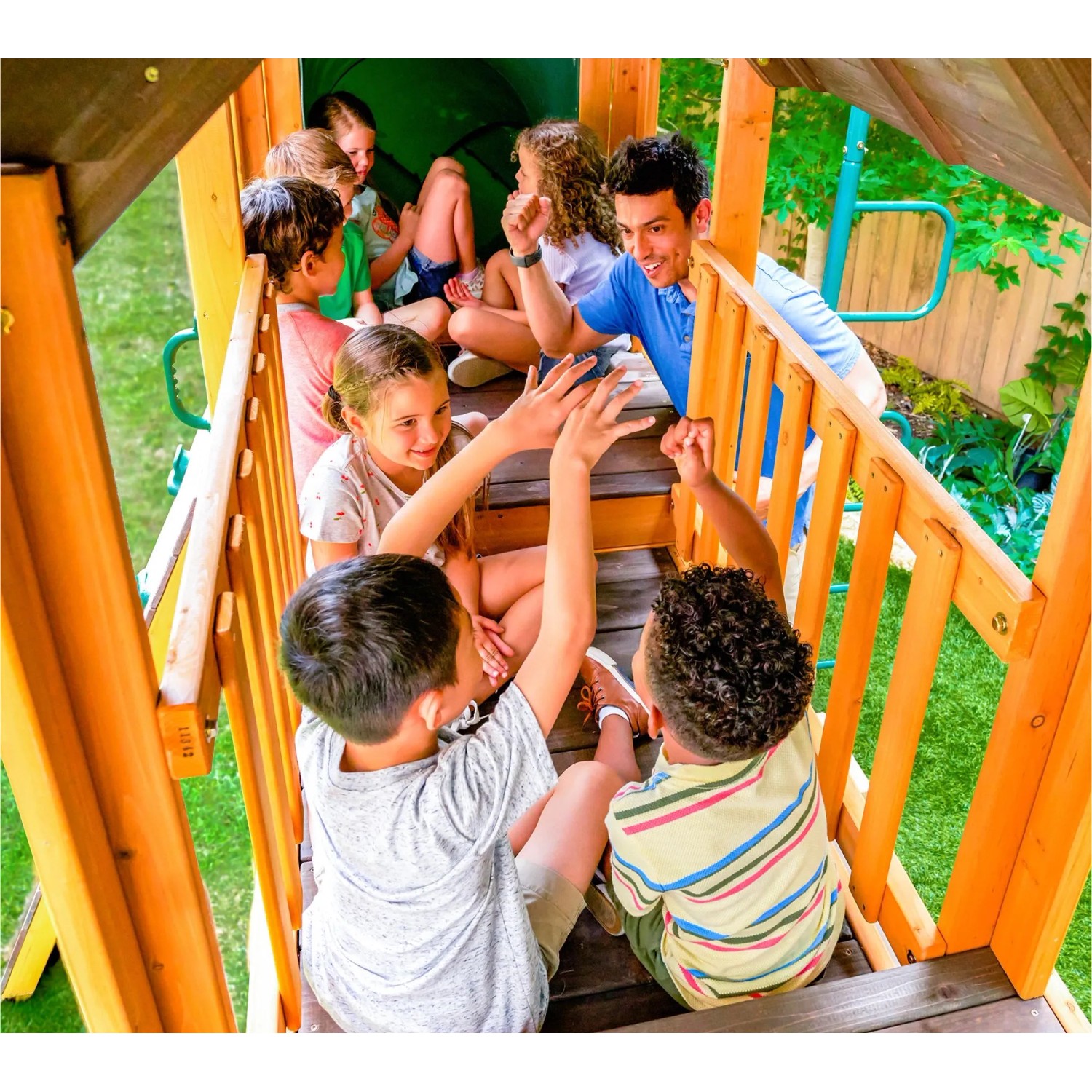 Kinder spielen auf dem Zwerkules Spielturm Bolzo mit Rutschen und Schaukel im Garten.