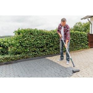 Mann trägt Ultrament Betonlasur Pflaster Frisch Grau mit Farbroller auf Pflastersteine auf.