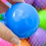 Blauer LittleTom Bällebadball (Ø 6 cm) mit CE-Kennzeichen in Hand, Pastellfarben im Hintergrund.