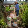Floragard Universal Hochbeet Grundfüllung (1260L) Säcke vor Gewächshaus mit Frau.