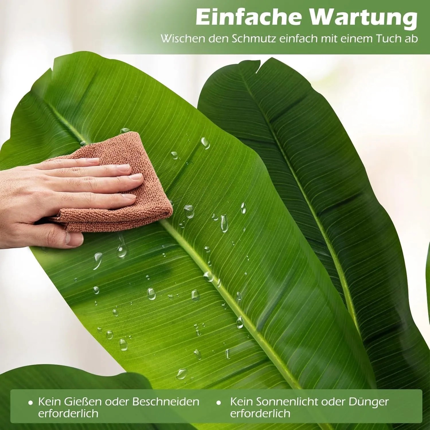 Hand wischt grünes Kunst-Bananenblatt mit Wassertropfen. Zeigt die einfache Reinigung der künstlichen Bananenbaum-Pflanze.
