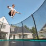 Grünes Salta Trampolin First Class 366x214 cm mit Sicherheitsnetz, Person springt.