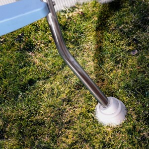 Detailaufnahme: Edelstahl Poolleiter mit Gummifuß auf Rasen. Sicherer Zugang zum Pool.