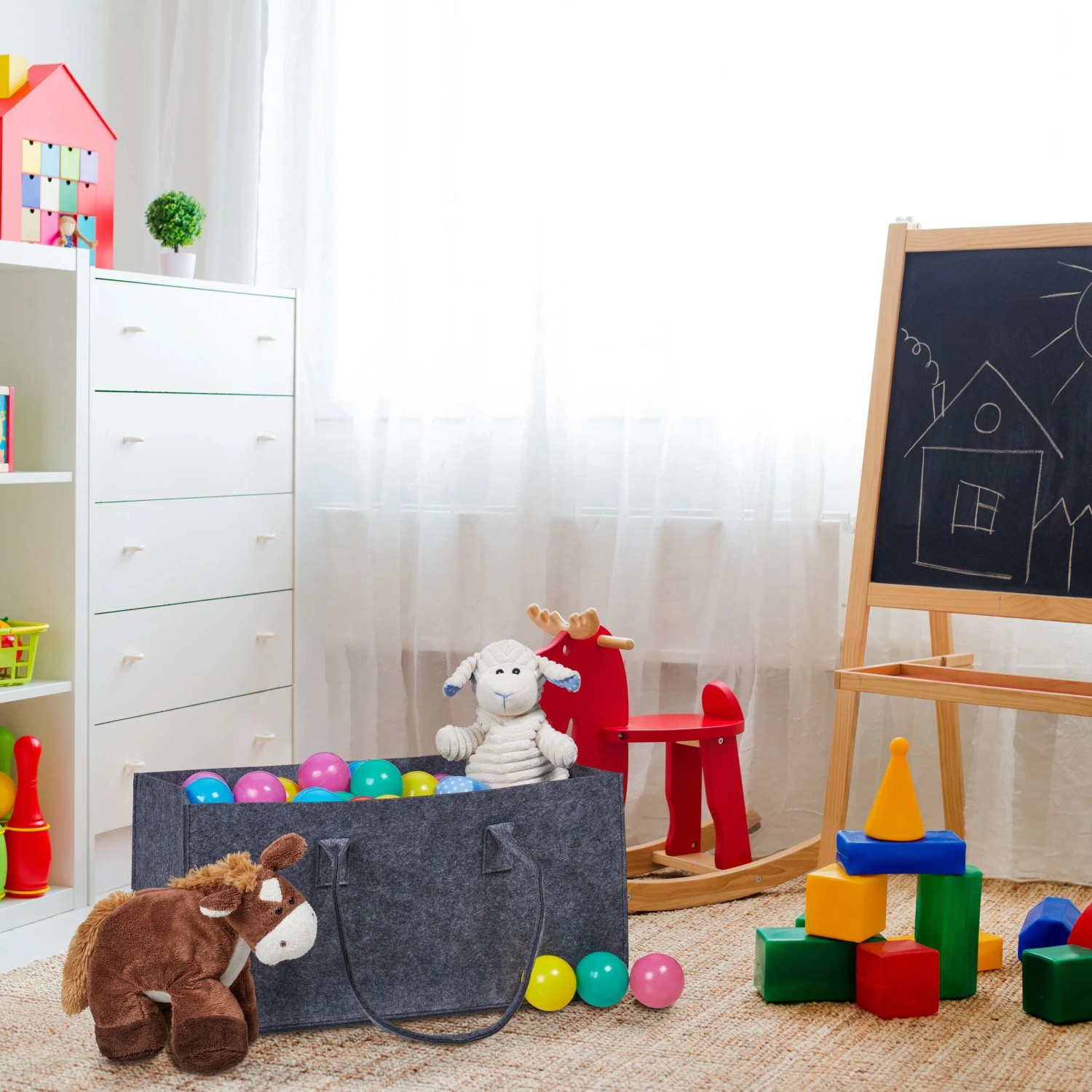 Dunkelgraue Filztasche mit Tragegriffen, gefüllt mit bunten Bällen und Spielzeug, als Aufbewahrungskorb im Kinderzimmer.