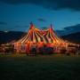 Bunte LED Partylichterkette beleuchtet ein gestreiftes Festzelt bei Dämmerung, perfekt für Außen & Veranstaltungen.