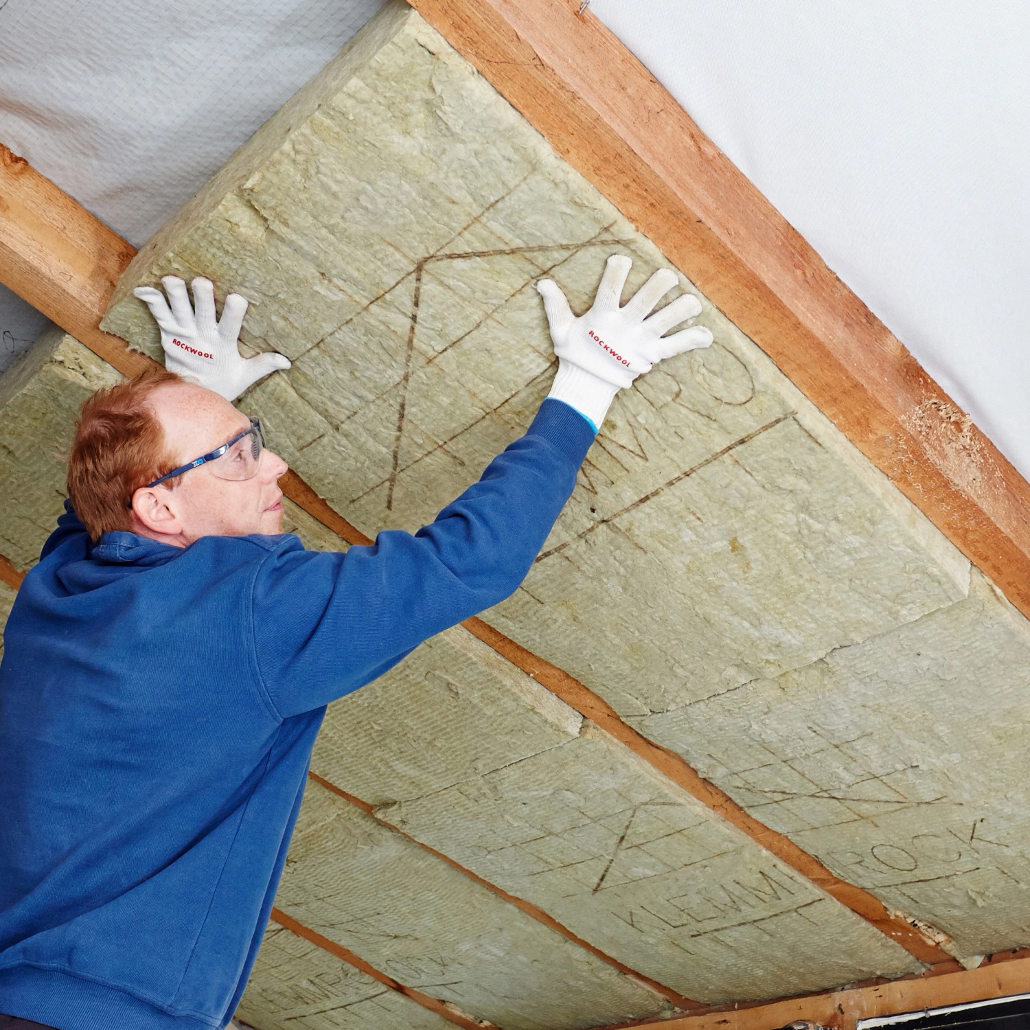 Ein Mann verlegt Rockwool Klemmrock Dämmwolle (120mm) zur Dachisolierung.