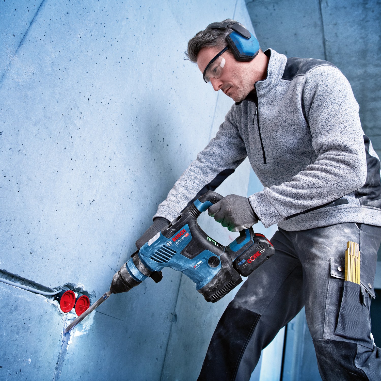 Mann bohrt mit Bosch Professional Akku-Bohrhammer GBH 18V-34 in Betonwand.