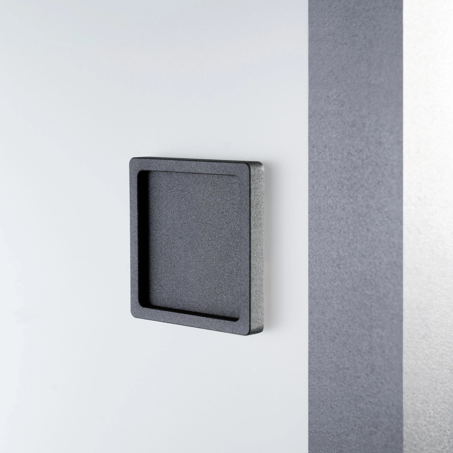Detailaufnahme: Quadratische, schwarze Griffmuschel der Loft+Mehr Schiebetür Klarglas.