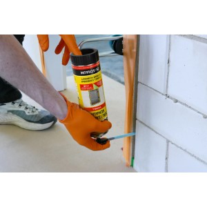 Hand trägt Soudal Zargenschaum 2K in Fuge einer Türzarge auf. Grüner PU-Montageschaum für Dämmung & Schallschutz.