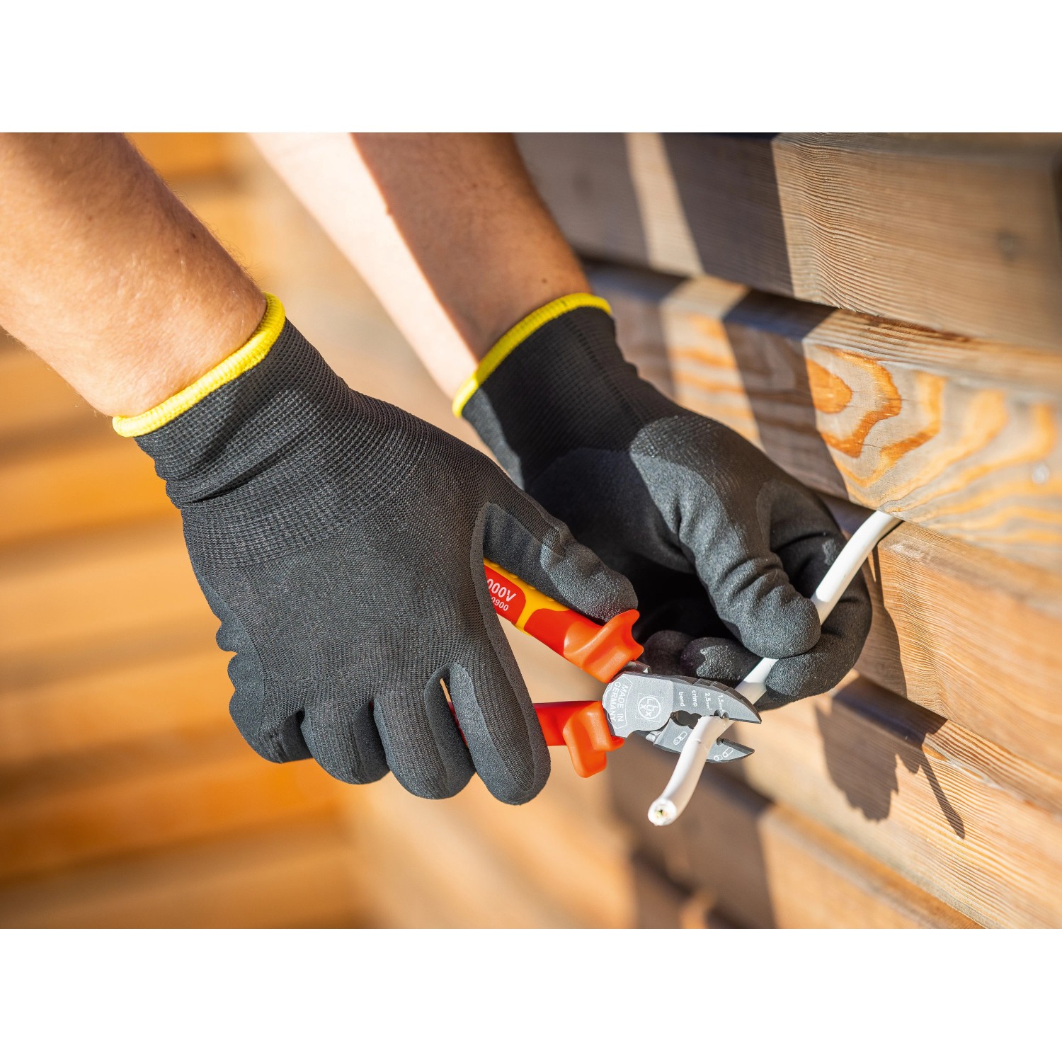 Hände mit LUX Arbeitshandschuhen Green Glove Gr. 8 schneiden Kabel mit einer Zange.