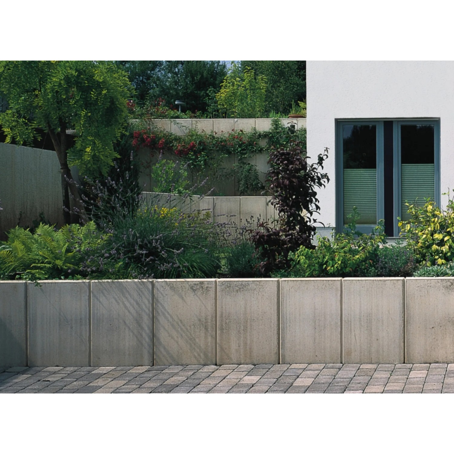Graue Mauerscheibe aus Beton (105x100x65cm) zur Böschungsbefestigung im Garten.