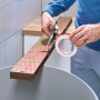 Anwendung Tesa Montageband für Fliesen/Metall: Person schneidet Klebeband mit Schere.