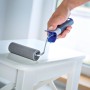 Hand hält LUX Schaumroller 11 cm beim Lackieren eines Tisches. Farbroller für glatte Untergründe.
