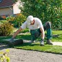 Mann verlegt Rollrasen im Garten. Spiel- und Sportrasen für eine schnelle Begrünung.