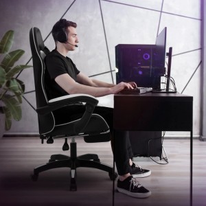 Schwarz-weißer Gaming Stuhl aus Kunstleder mit ausgefahrener Fußstütze, ein Gamer sitzt am PC.