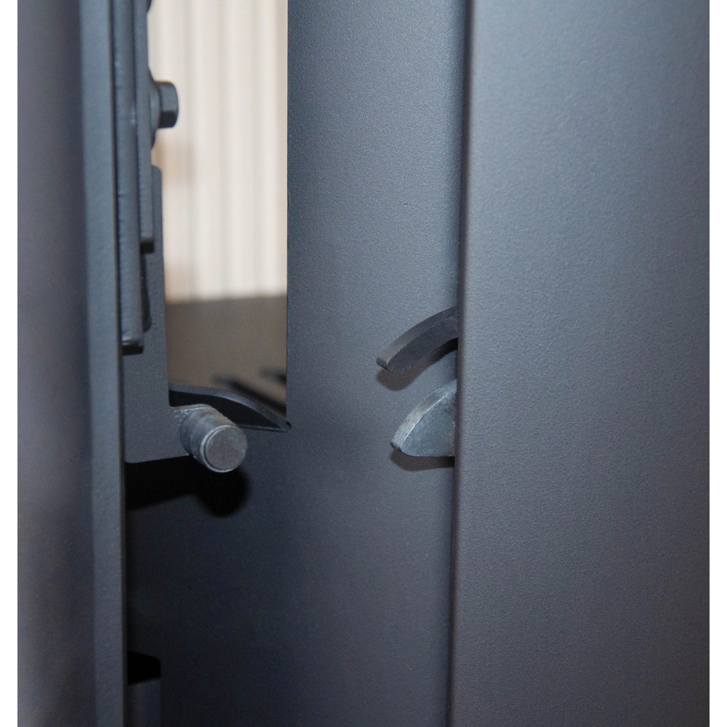 Detailaufnahme: Justus Island 5 2.0 Kaminofen, gussgrau mit Specksteinverkleidung, Fokus auf Verschlussmechanismus.