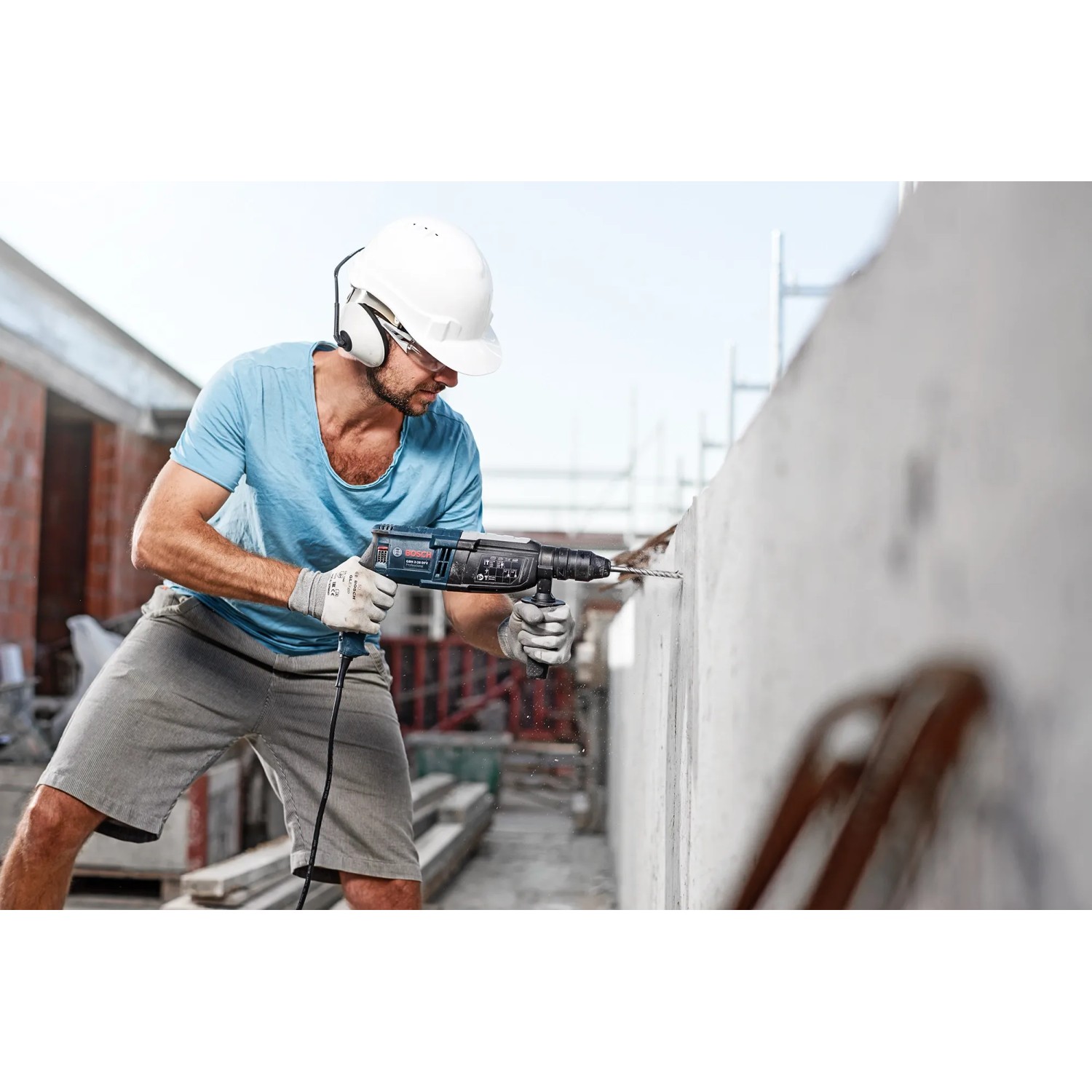 Mann bohrt mit Bosch Hammerbohrer SDS Plus-3 ein Loch in Betonwand.