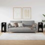 Zwei moderne schwarze Beistelltische aus Holzwerkstoff mit Ablagen neben einem Sofa im Wohnzimmer.