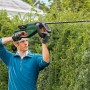 Mann schneidet Hecke mit Bosch Akku-Heckenschere UniversalHedgeCut 18-55. Heckenschneider im Einsatz.