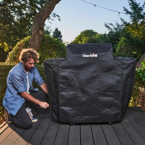 Char-Broil Grillabdeckung Smart-E für Elektrogrill, Wetterschutzhaube wird von Mann befestigt.