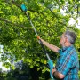Mann schneidet Äste mit Gardena Akku-Teleskop-Hochentaster TCS 20/18V. Astsäge im Einsatz.