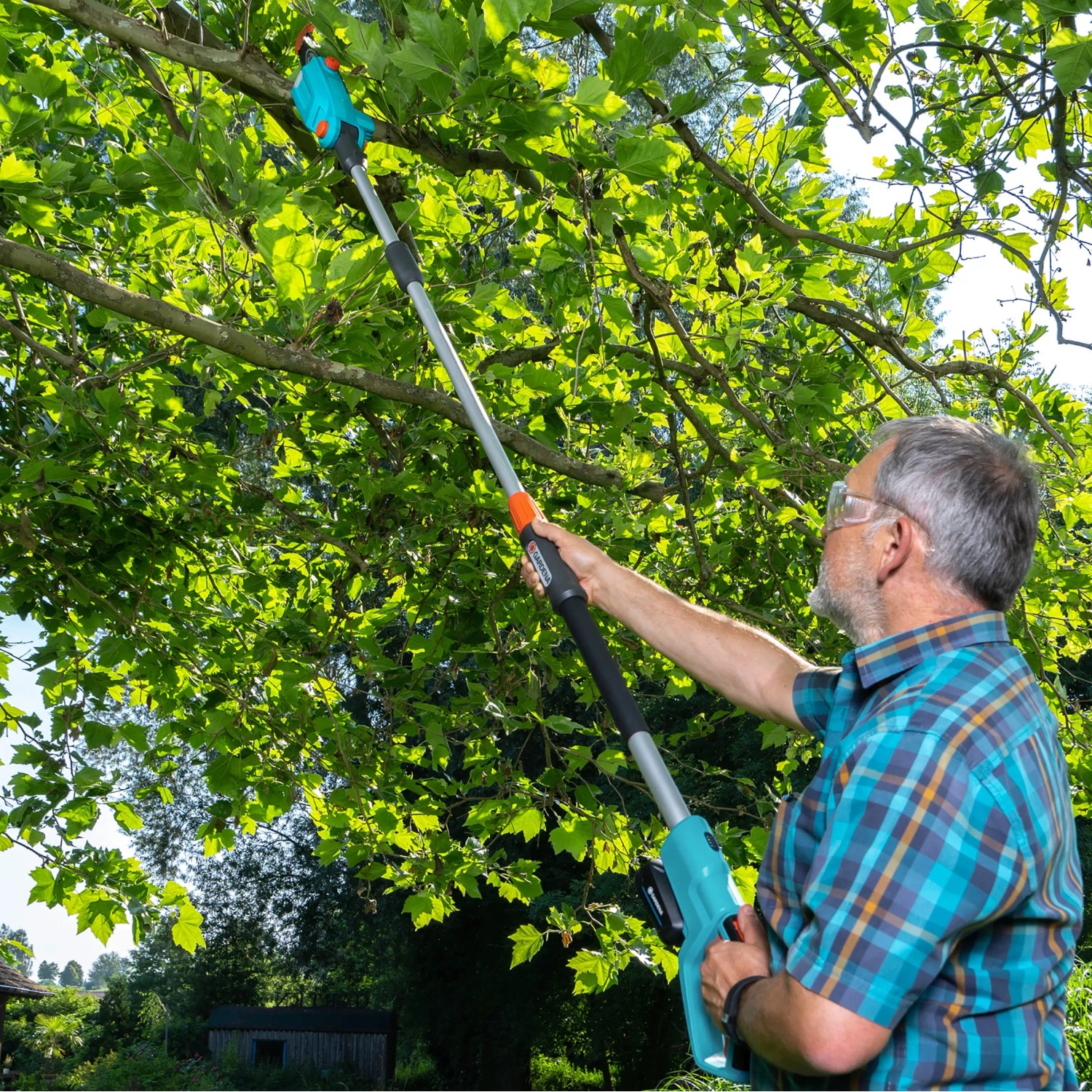 Mann schneidet Äste mit Gardena Akku-Teleskop-Hochentaster TCS 20/18V. Astsäge im Einsatz.