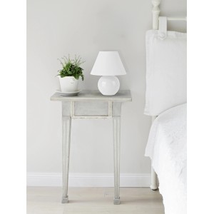 Weiße Tischleuchte Primo auf Nachttisch mit Pflanze. Design-Tischlampe mit Stoffschirm.