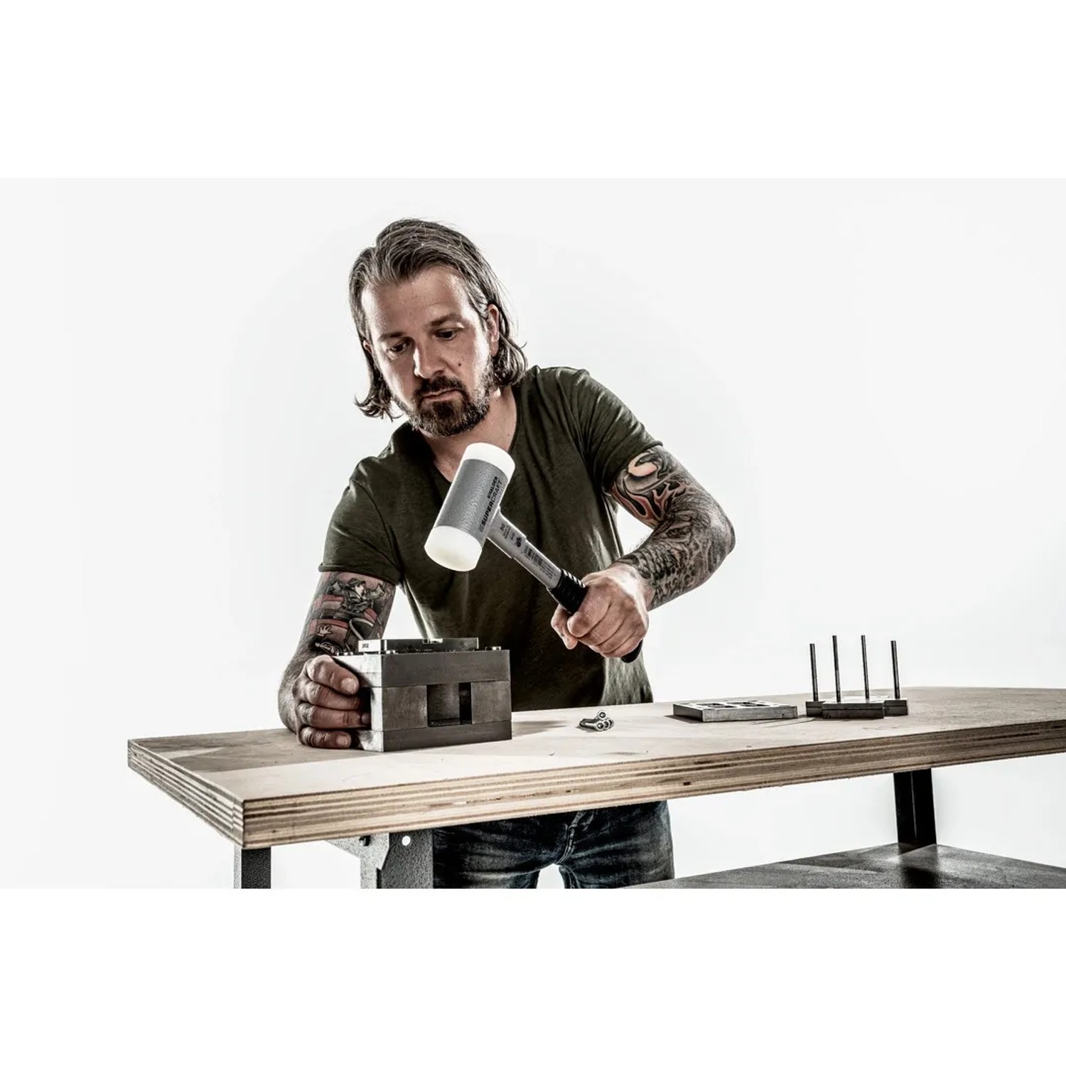 Mann nutzt Halder Supercraft Schonhammer (Ø 45 mm) auf Werkbank. Rückschlagfreier Hammer mit Stahlrohrstiel für präzise Arbeit.