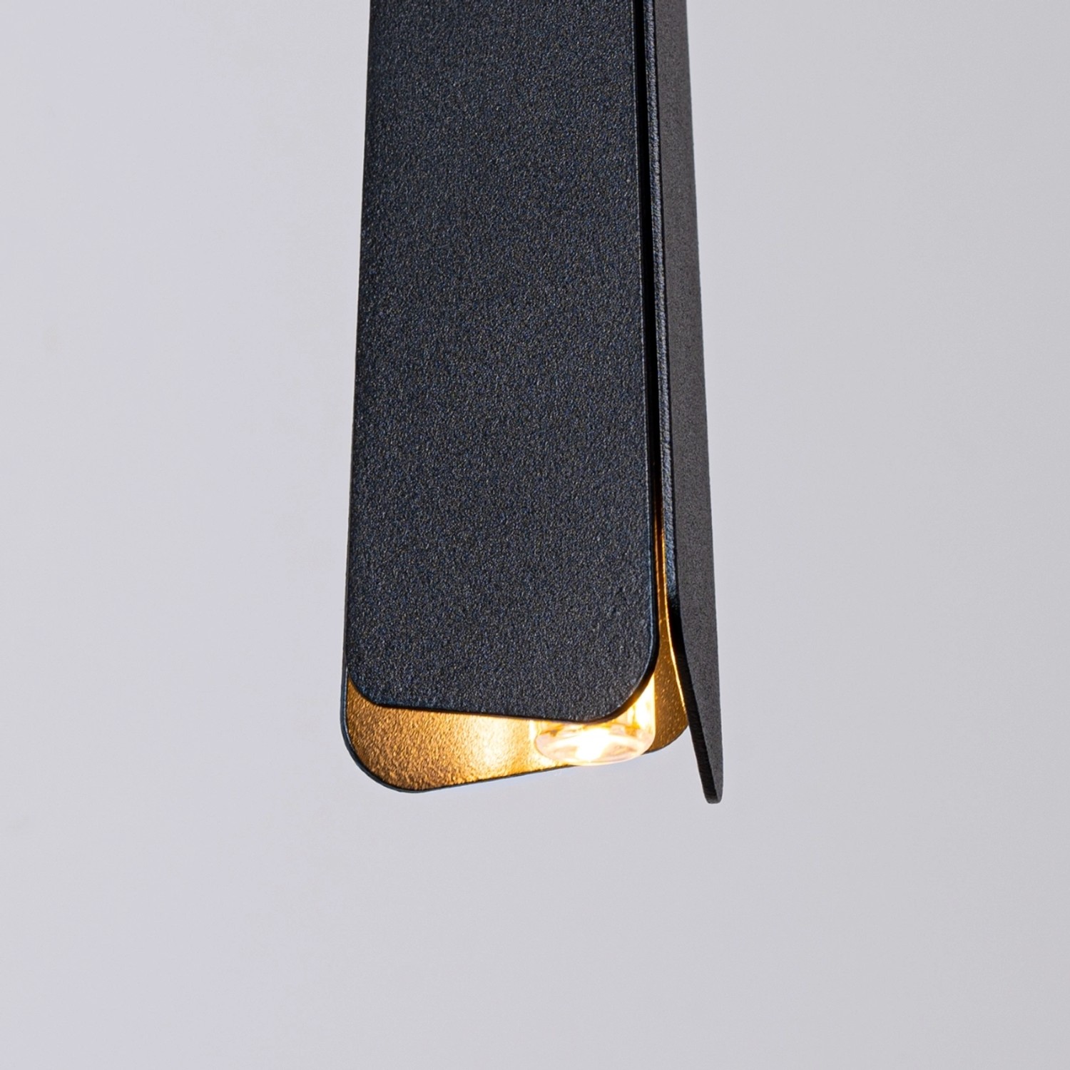 Detailaufnahme: Schwarze Sollux Lighting Hängeleuchte Prysm 1 mit goldfarbenem Akzent.