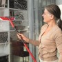 Frau reinigt Fenster mit Vileda Profi-Fensterwischer-Set mit Stiel.