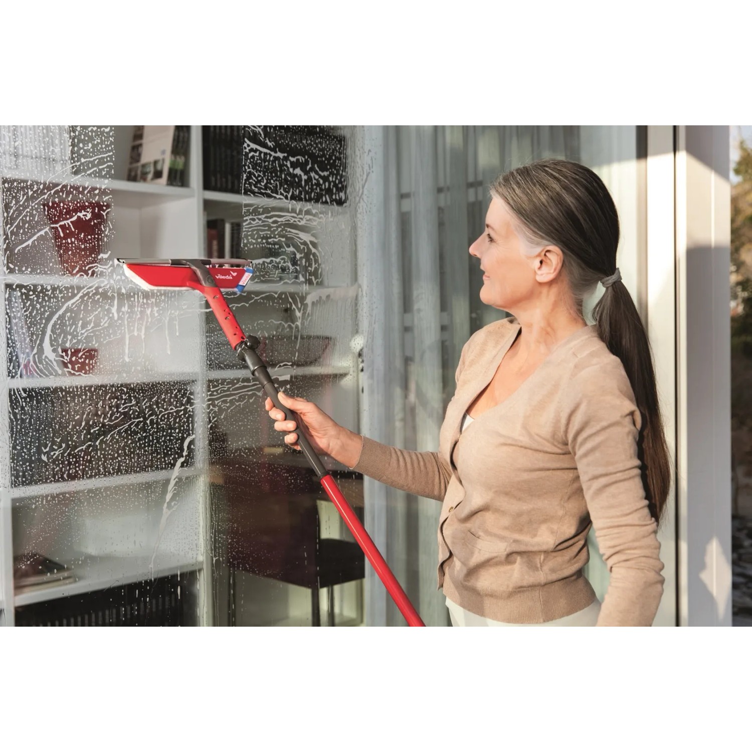 Frau reinigt Fenster mit Vileda Profi-Fensterwischer-Set mit Stiel.