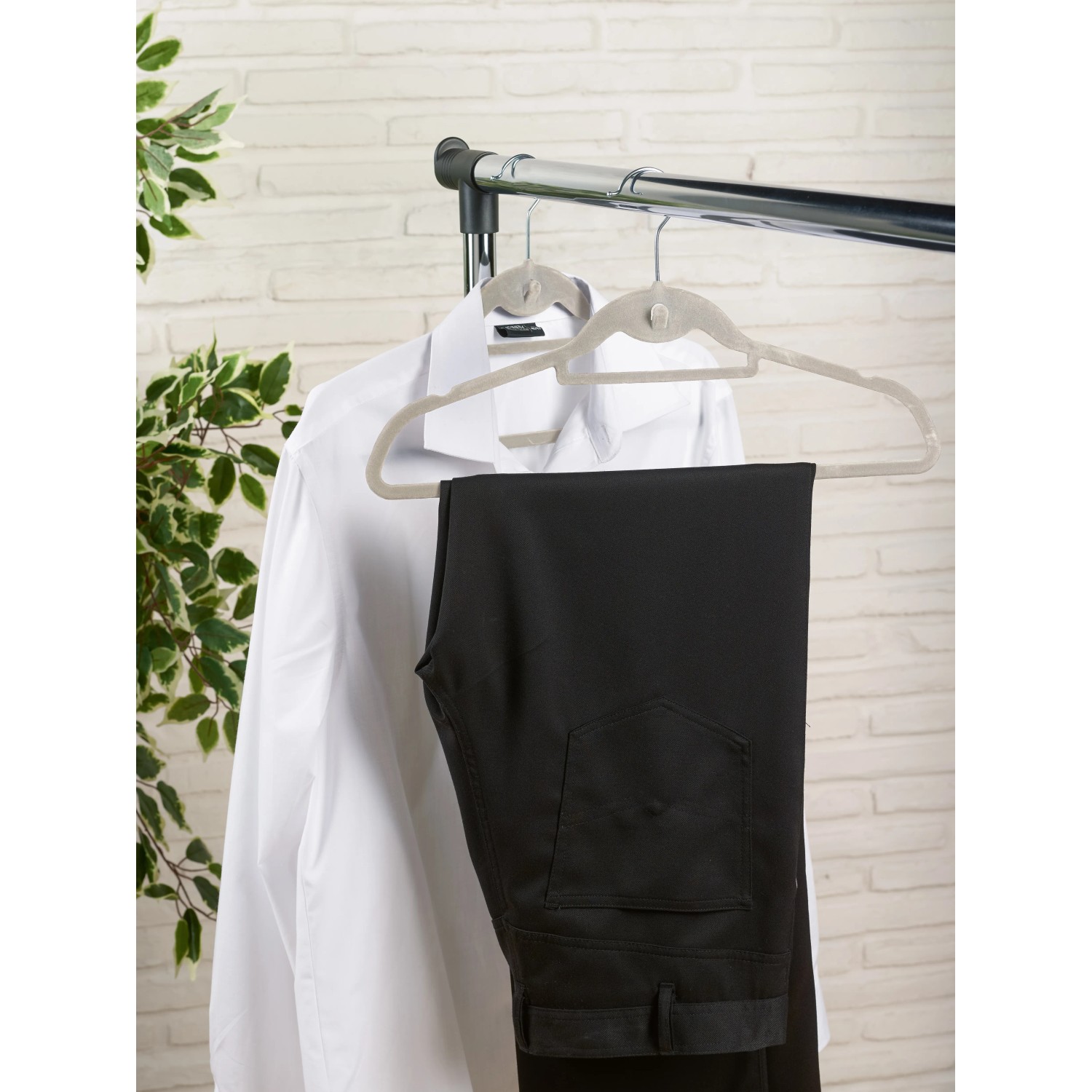 Zwei beflockte Kleiderbügel mit Hemd und Hose am Kleiderständer. Textile Aufbewahrung.