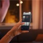 Frau steuert Philips Hue Lampe per App auf dem Smartphone. Smart Home Beleuchtung.