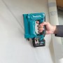 Makita Akku-Tacker ST113DSMJ (10,8 V) in Aktion: Hand tackert Klammer in weiße Folie. Akkugerät für Heimwerker.