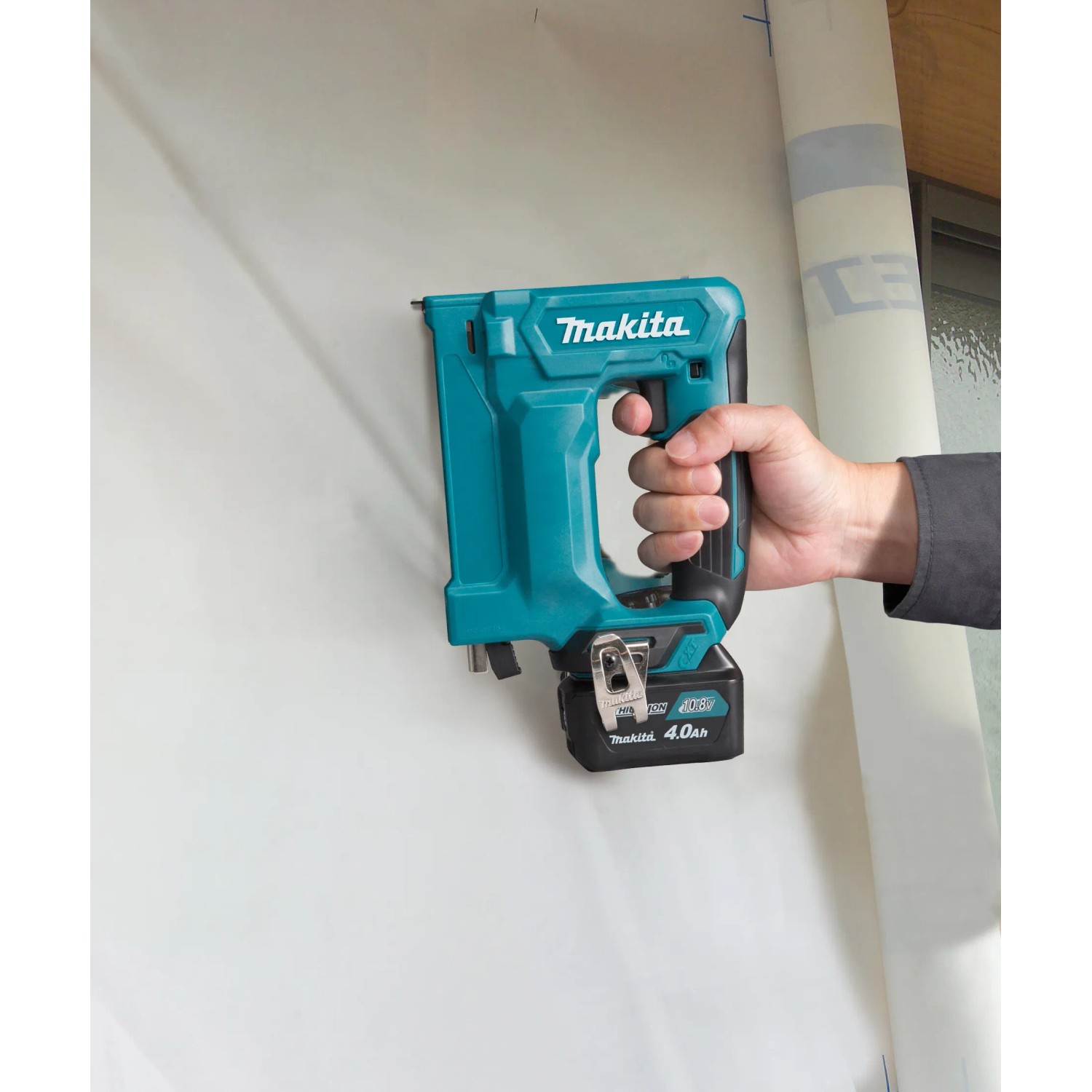 Makita Akku-Tacker ST113DSMJ (10,8 V) in Aktion: Hand tackert Klammer in weiße Folie. Akkugerät für Heimwerker.