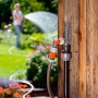 Gardena Wasserstecker an Holzwand mit angeschlossenem Gartenschlauch im Einsatz.