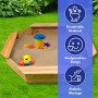 Sechseckiger Holzsandkasten Coemo Sally mit Spielzeug und Bodenplane im Garten.